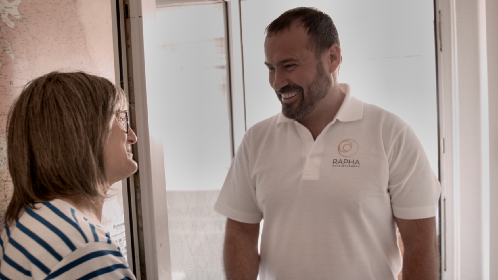 RAPHA PHYSIO physiotherapist greeting a patient at their front door