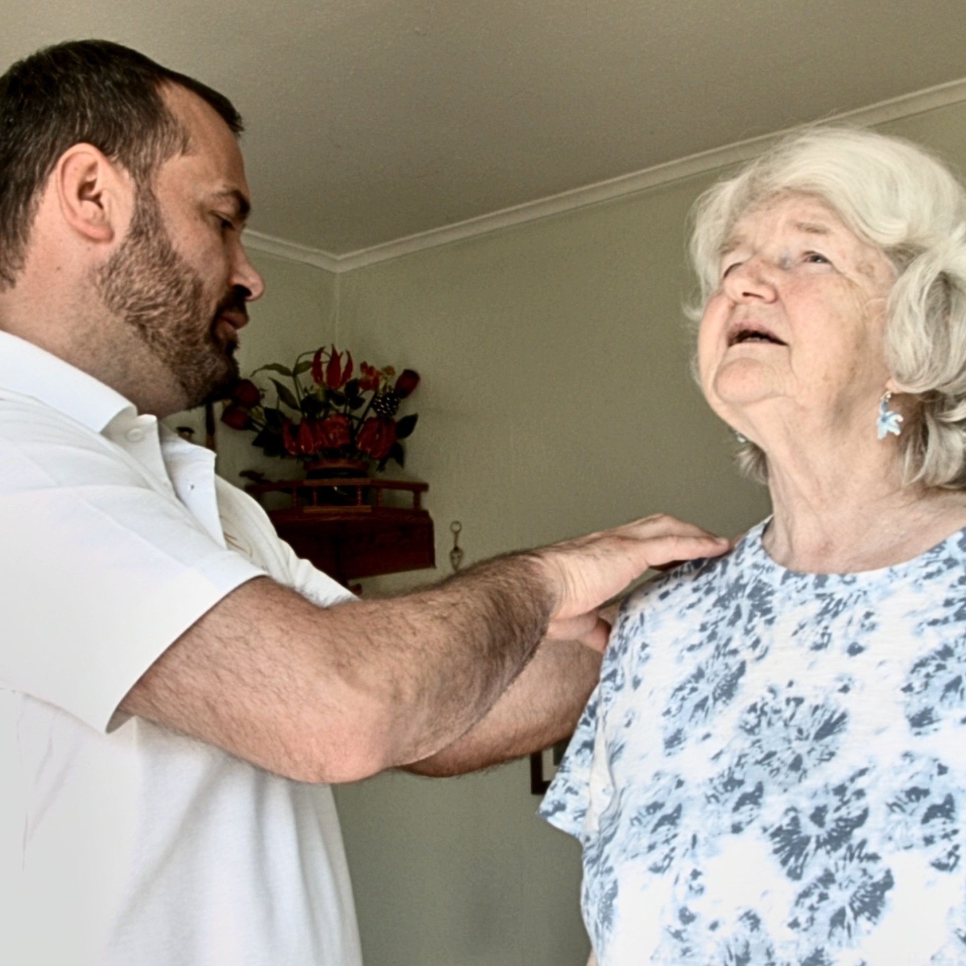 Physiotherapist treating an older patient's shoulder at home